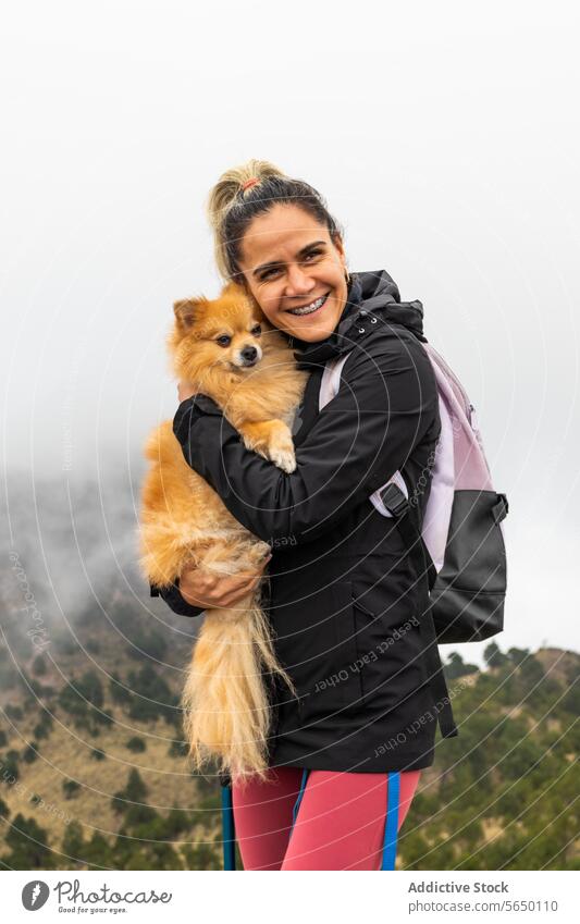 Happy hiker with Pomeranian in Ajusco dog embrace smiling mountainous landscape misty Cumbres del Ajusco national park Pico del Águila Mexico City outdoor joy