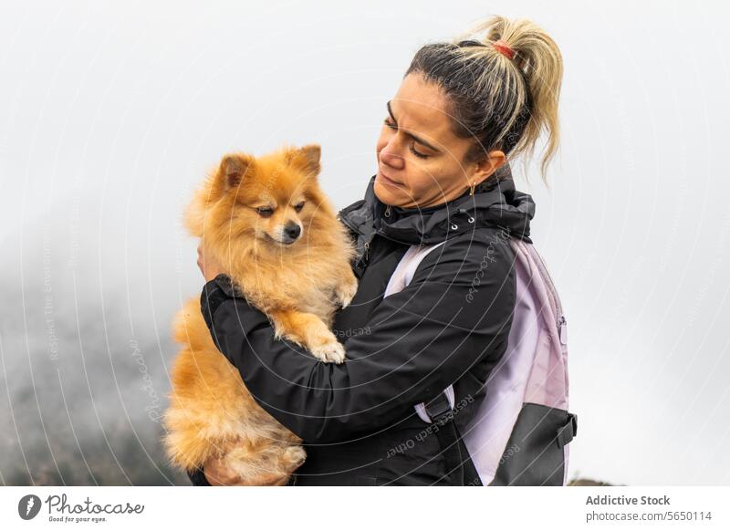 Side view of woman with Dog in Mountains Pomeranian dog holding outdoors Cumbres del Ajusco national park Pico del Águila foggy mountain Mexico City pet nature