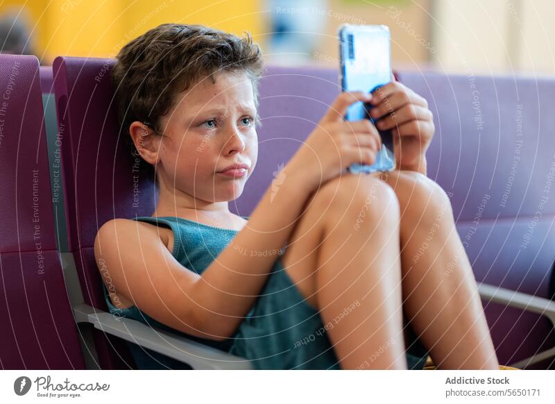 Boy Using Smartphone in Airport Waiting Area boy smartphone airport waiting area seating child travel terminal passenger digital technology entertainment