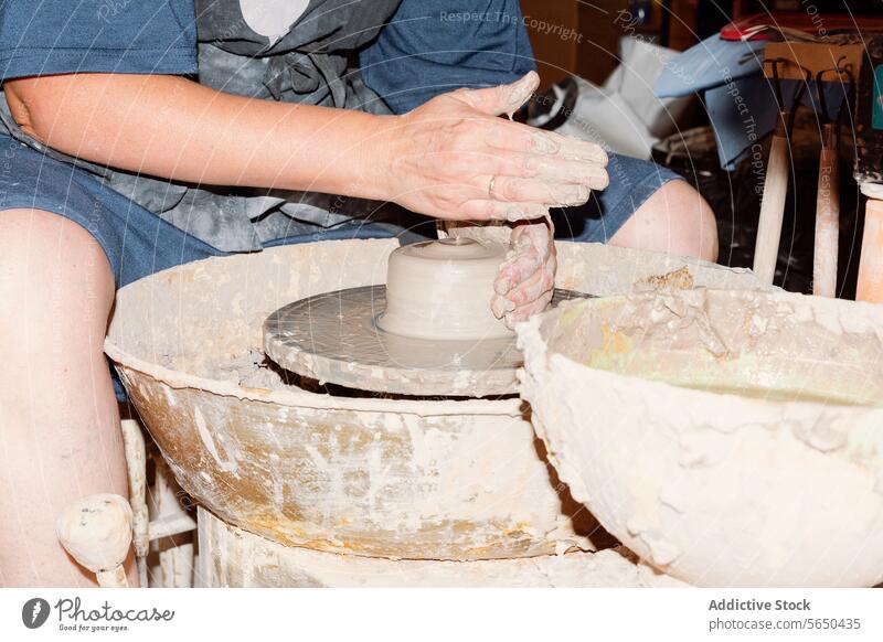 Focused anonymous craftswoman working on pottery wheel artisan clay shape handmade professional creative workshop female skill small business create process
