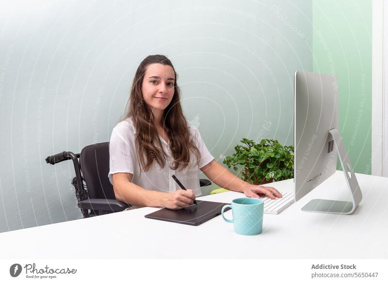 Professional Woman Working in wheelchair at a Modern Desk Setup woman professional desk computer digital tablet office work focused clean minimalist modern