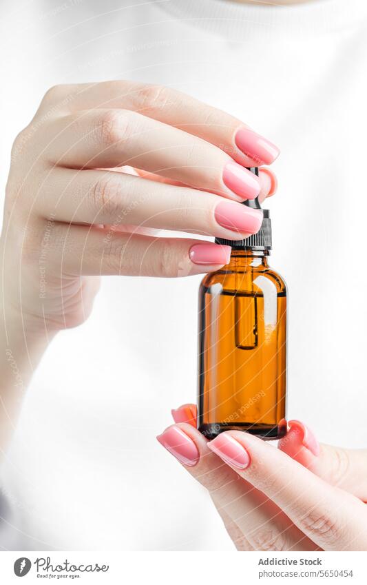 Close-up of female hands holding a dropper bottle. woman nail polish manicure pink amber glass skincare beauty close-up cosmetic liquid treatment essential oil
