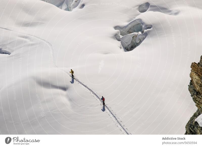 High angle of anonymous skiers in warm clothes Traversing a Snow-Covered Glacier in Zermatt, Switzerland glacier snow ice ridge trail alpine terrain
