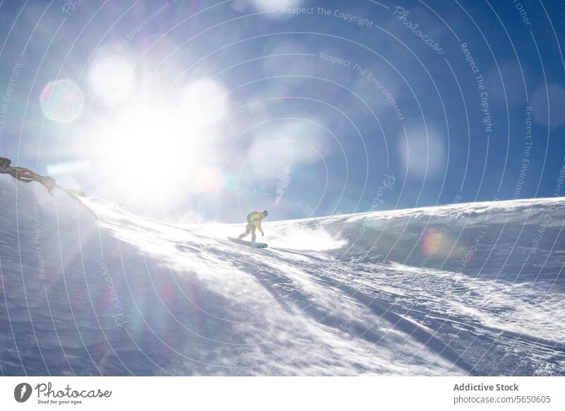Low angle of Anonymous man snowboarding on mountain against sun and blue sky in Zermatt Tourist Snow Snowboard Sport Majestic Mountain Slope Landscape