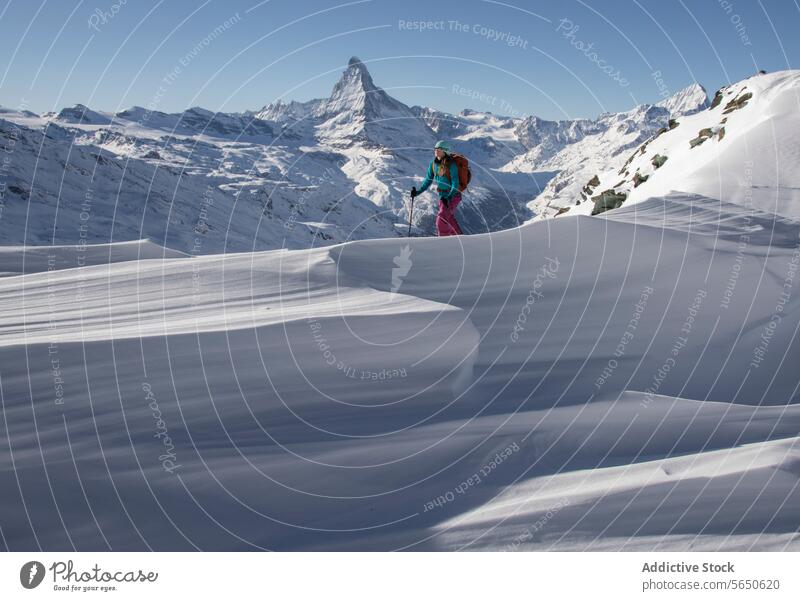 Side view of anonymous Woman in warm clothes skiing on snowy mountain during vacation in Zermatt Tourist Ski Walk Backpack Snow Mountain Hiker Majestic Peak