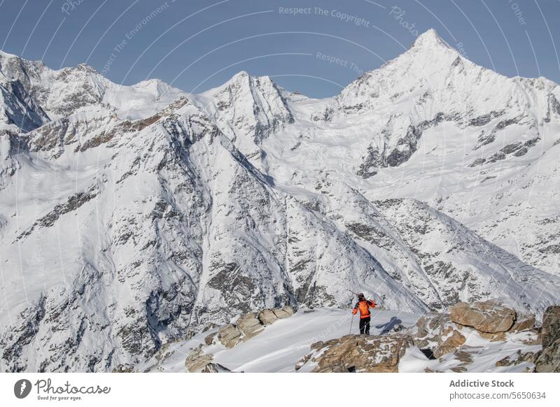 Full body of unrecognizable backpacker in warm clothes standing on rock against snowy mountains during vacation in Zermatt Tourist Ski Backpack Snow Mountain