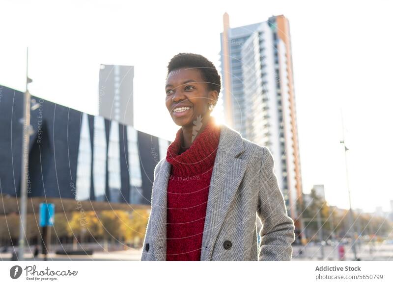Confident African American businesswoman standing against urban buildings downtown skyscraper city self assured weekend outerwear confident serious emotionless