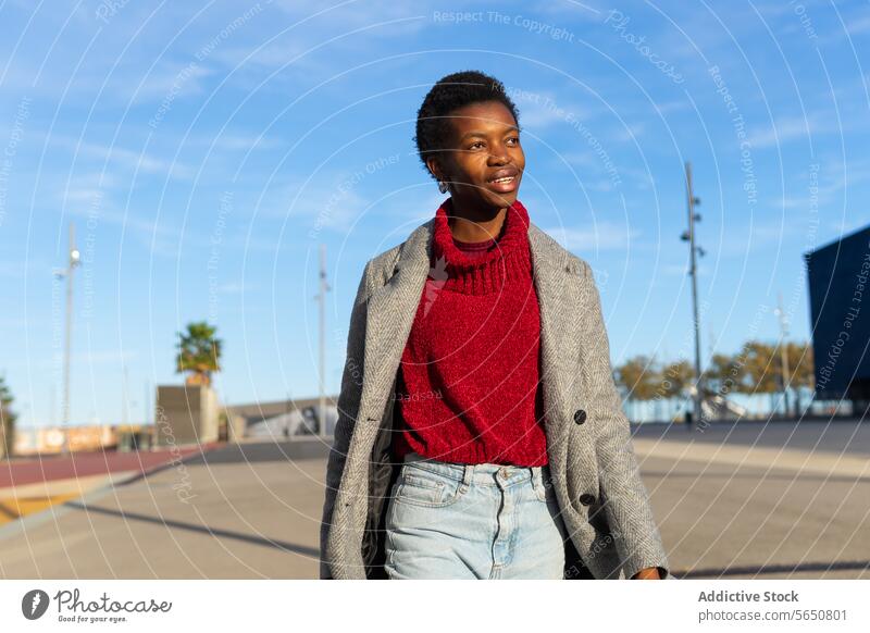 Happy black woman strolling in city walk weekend free time town urban sunlight smile happy female adult african american ethnic afro short hair style autumn