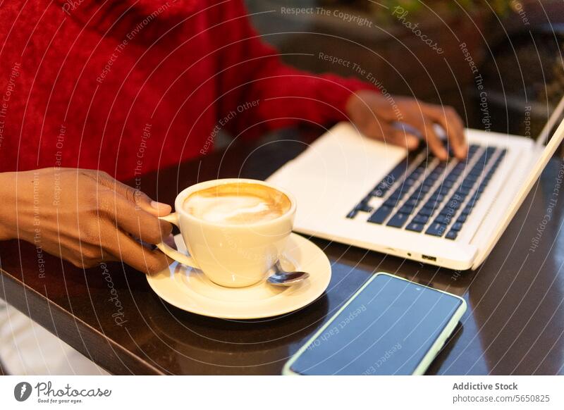 Crop freelancer working on laptop in cafe woman using drink cappuccino coffee typing female adult african american black ethnic independent modern startup
