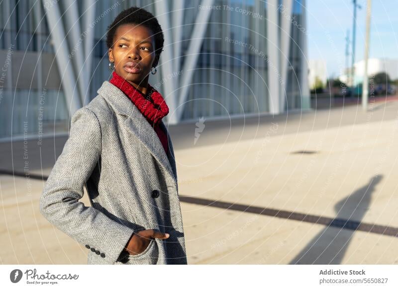 Confident African American businesswoman standing against urban buildings downtown skyscraper city self assured weekend outerwear confident serious emotionless