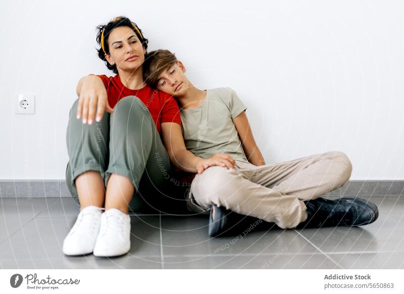 Teenager sitting on floor with mother and leaning head on mother shoulder son rest relocate new house teenager parent apartment boy together woman home relax