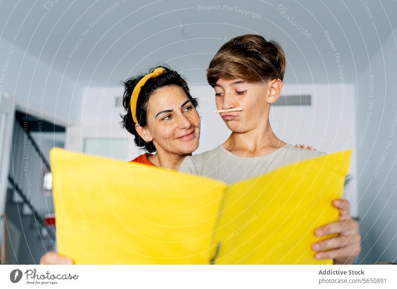 Mother and son having fun while studying documents on yellow file mother examine enjoy time together woman boy relocate apartment love home check parent casual