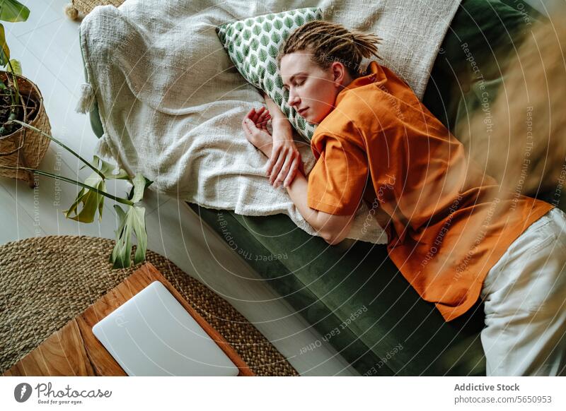 Young woman sleeping on comfortable sofa with cushion at home near laptop apartment couch relax asleep nap connection internet freelance pillow flat digital