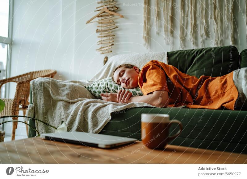 Young woman sleeping on comfortable sofa with cushion at home near laptop and mug apartment couch relax asleep nap connection internet freelance pillow flat