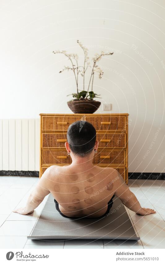 Young man doing rehabilitation exercise on mat at home stretch shirtless back therapy mark balance wellness fit recreation flexible strength physical calm