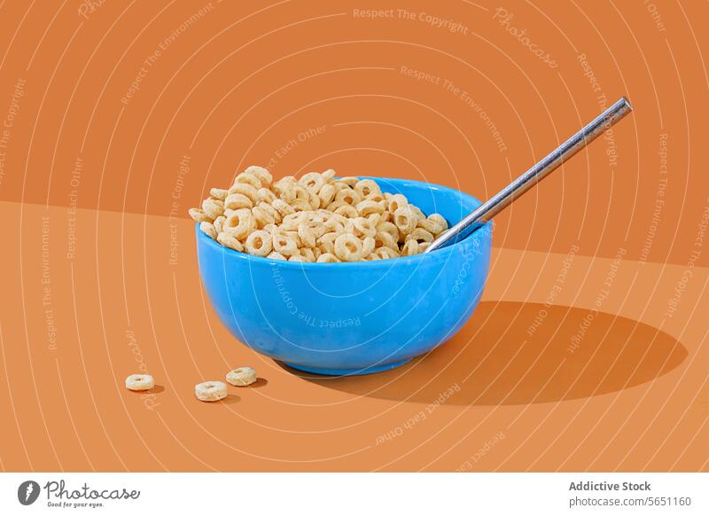 Blue bowl of cereal with milk on an orange background spoon vibrant blue breakfast food snack loop-shaped dairy nutrition meal morning colorful minimalism