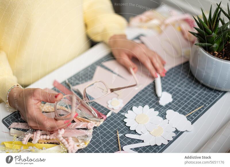 Crafting enthusiast working with paper and decorations craft flower ribbon spectacles cutting mat hand crafting hobby scissors creative art diy homemade project
