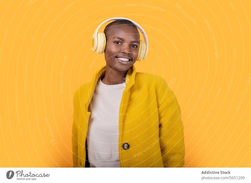 Happy black young woman enjoying music through wireless headphones cheerful listening ethnic african american happy smile casual attire lifestyle cool device