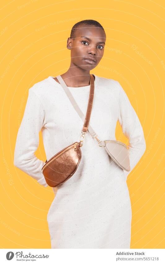 Young black woman in sling bag isolated on yellow background serious trendy slim fashion confident african american expression elegance variation attractive