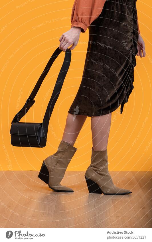 Trendy woman wearing boots holding handbag on floor fashionable high heels purse walking hardwood yellow background trendy crop elegance accessory isolated