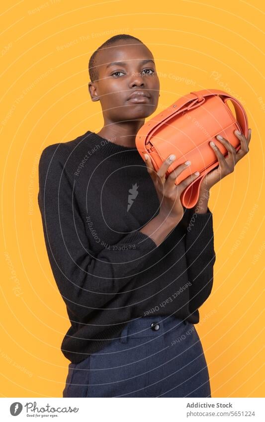 Confident black woman with stylish purse against yellow background confident trendy orange short hair fashion young holding portrait isolated african american