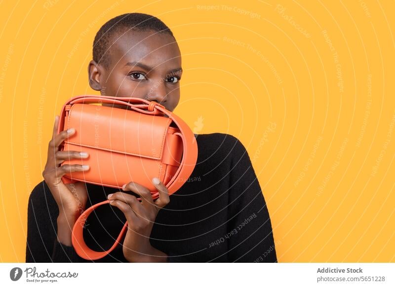 Confident black woman with stylish purse against yellow background confident trendy orange short hair fashion young holding portrait isolated african american