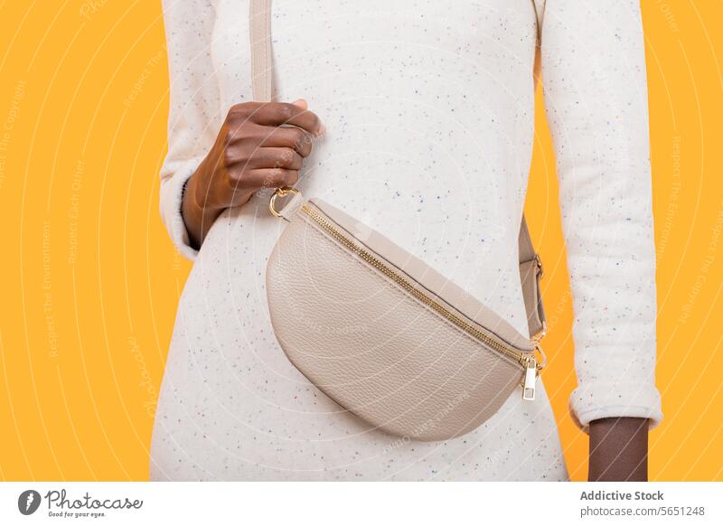 Anonymous fashionable black woman in sling bag isolated on yellow background trendy accessory purse african american elegance strap lifestyle white material