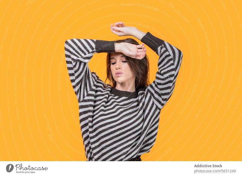 Trendy woman with hands on head isolated on yellow background trendy casual attractive looking down fashionable striped pattern standing confident portrait