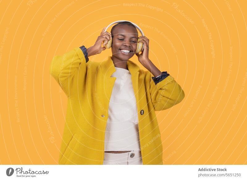 Happy black young woman enjoying music through wireless headphones cheerful listening ethnic african american happy smile casual attire lifestyle cool device