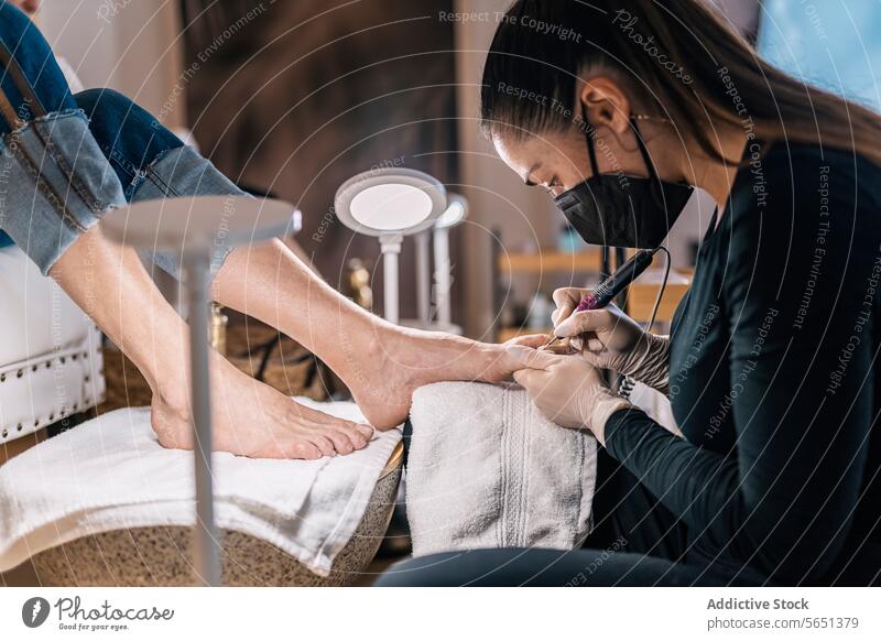 Crop woman getting pedicure treatment in beauty salon women beautician procedure artist leg feet client customer mask professional service female protect safety