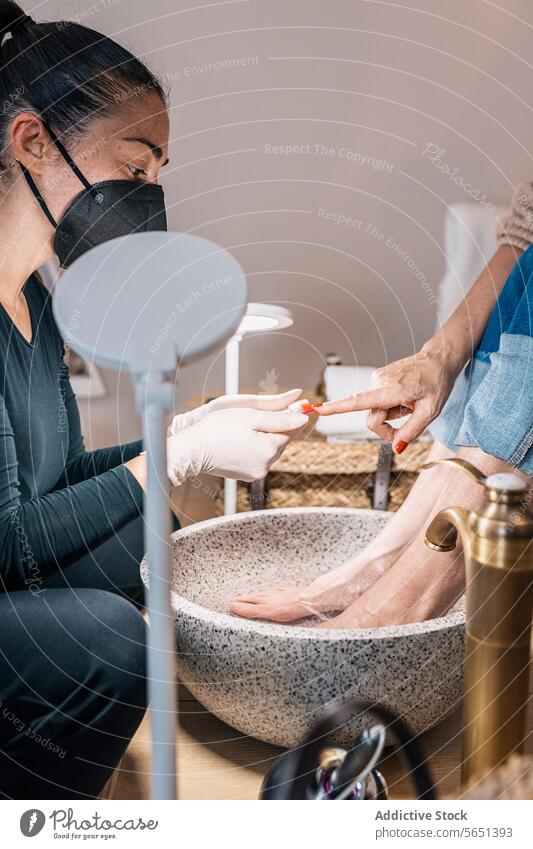 Crop woman undergoing beauty treatment in salon women manicure pedicure footbath apply nail polish beautician client mask care procedure service varnish