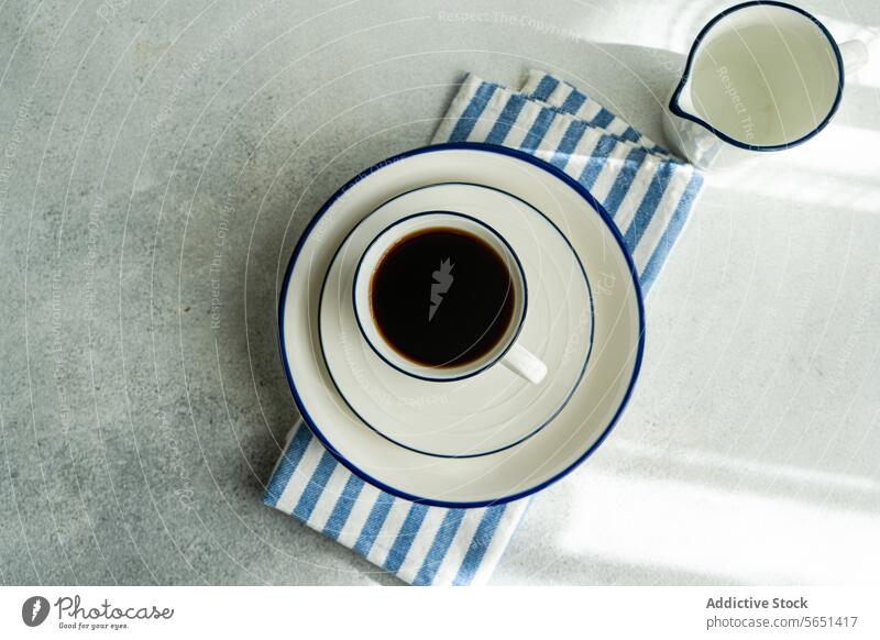 Freshly brewed drip coffee in a minimalist setting cup saucer napkin stripe milk jug white tabletop ceramic drink morning beverage cafe aroma top view breakfast