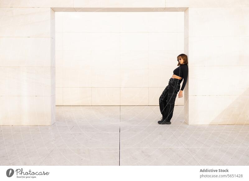 Modern woman posing against a minimalist architecture backdrop modern fashion structure contemporary urban vibe style confident young attire black stark female