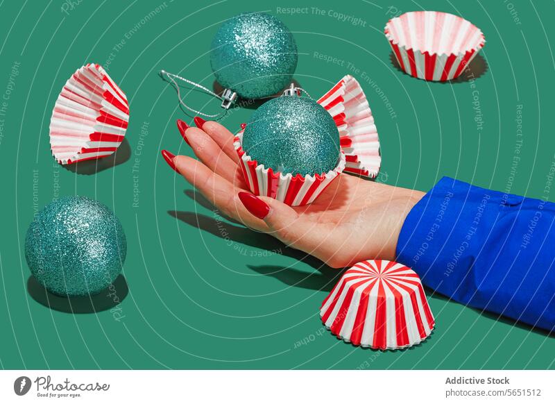 Hand Presenting a Christmas Bauble Christmas gift hand red nails bauble woman anonymous turquoise glitter cupcake liner striped presentation decoration festive