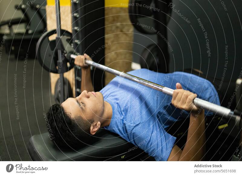 Fitness enthusiast young man performs bench press in gym fitness workout exercise barbell lifting health sport strength training athlete focus determination