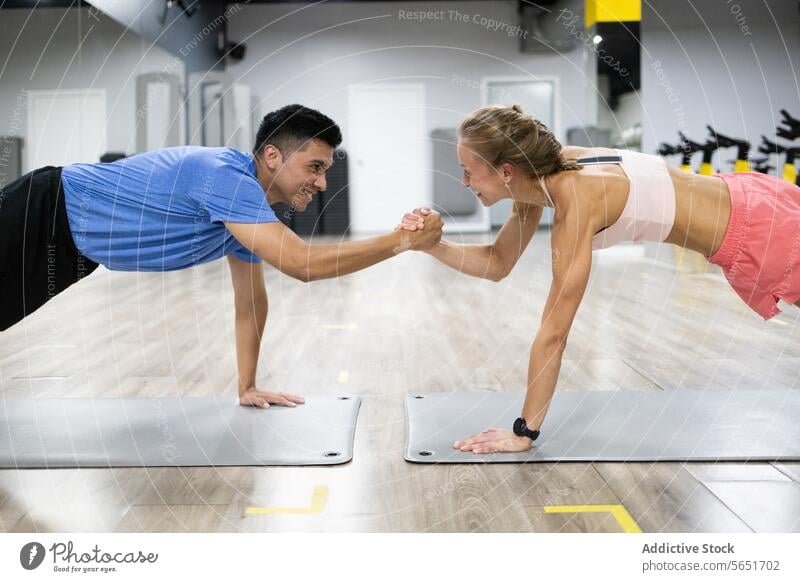 Fitness duo in plank position with motivational fist bump fitness challenge gym exercise workout strength healthy lifestyle modern training people man woman
