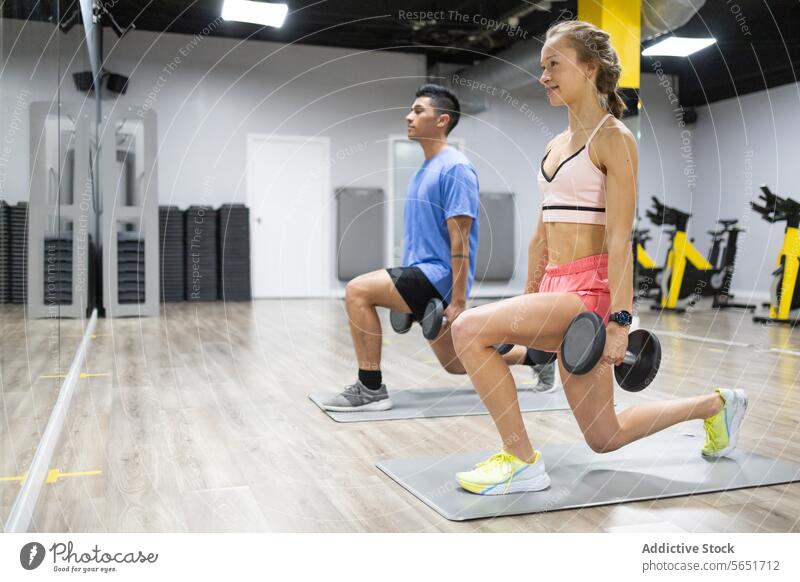 Fitness Enthusiasts Performing Lunges in Gym fitness gym workout exercise lunge dumbbell training health focus active lifestyle strength endurance equipment