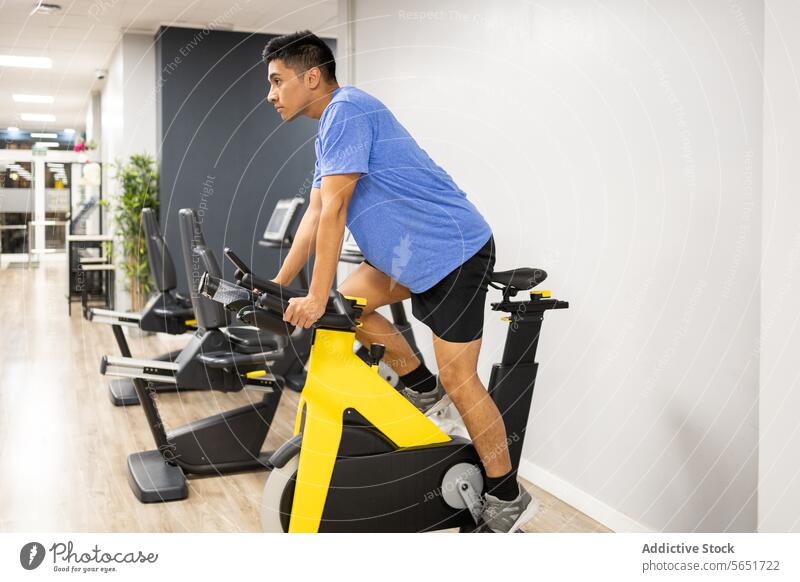 Man exercising on a stationary bike at the gym man exercise fitness workout health lifestyle riding equipment indoor cycle training sport active physical