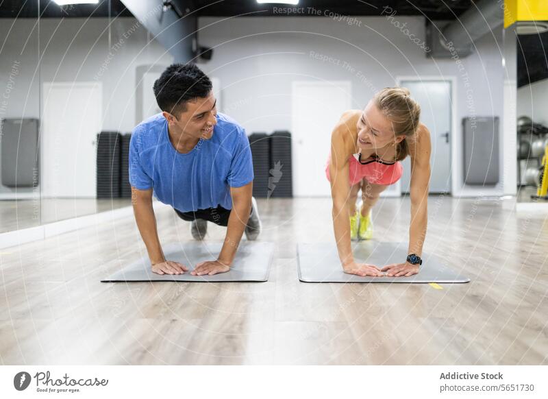 Fitness partners doing push-ups in a modern gym fitness exercise happy workout health sport active partnership challenge strength training man woman mat
