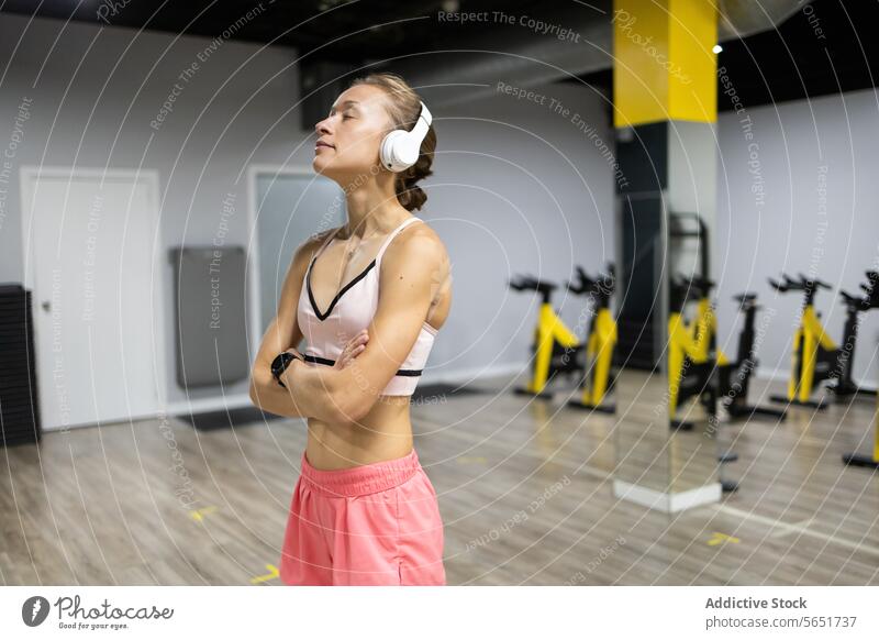 Fitness enthusiast takes a break with headphones in modern gym woman fitness workout reflecting exercise health sports bra athleisure active lifestyle equipment