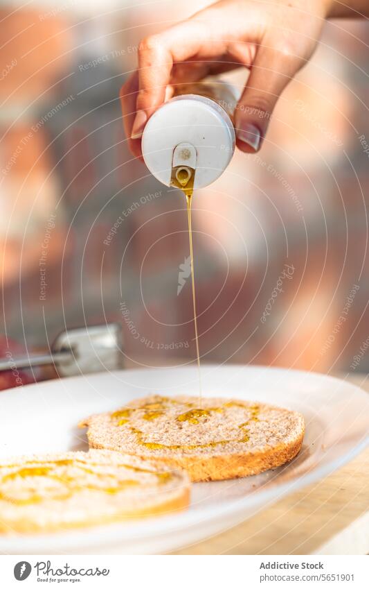Drizzling honey on a slice of wholegrain toast drizzle breakfast pour hand jar golden fresh plate white bread close-up food topping sweet healthy nutrition
