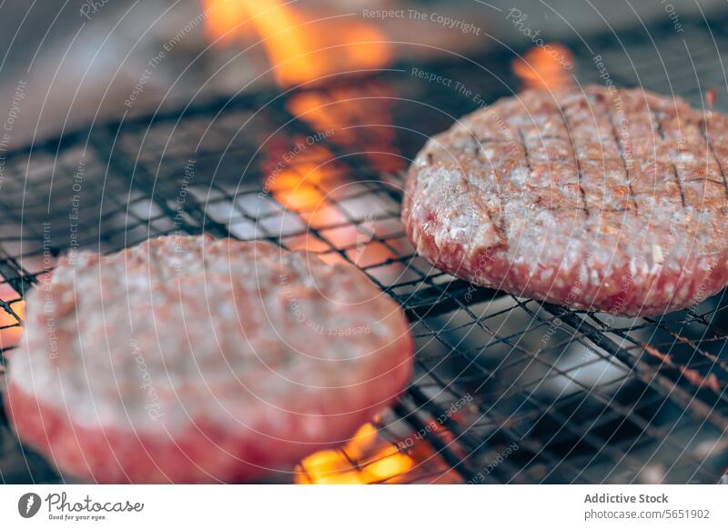 Juicy hamburgers grilling over open flames barbecue cooking food close-up meat beef juicy charred meal dinner patty grilled outdoor summer heat fire smoke