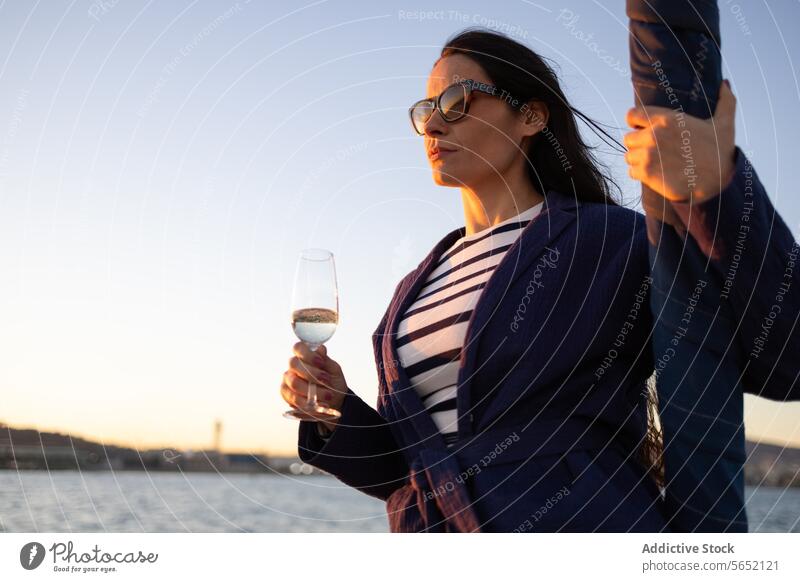 Young woman with glass of drink standing against sea water ocean yacht outfit sailboat shore tourism idyllic modern aqua ripple coast clear paradise seaside