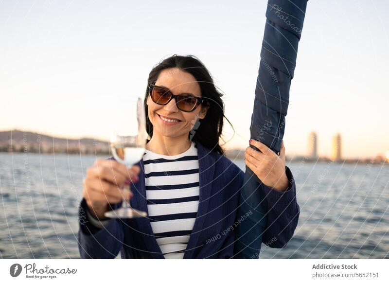 Young woman with glass of drink standing against sea water ocean yacht outfit sailboat shore tourism idyllic modern aqua ripple coast clear paradise seaside