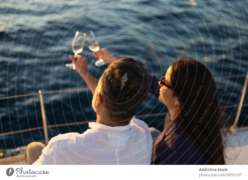 Back view couple clinking wineglasses in yacht against sea love romantic toast ocean beach alcohol date resort drink cheers enjoy pleasure seascape romance