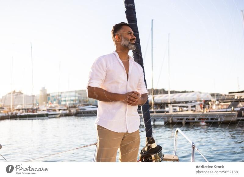 Smiling bearded male in white shirt looking away yacht against blue sea and sky man smile happy mobile travel relax trip boat content vessel nature seascape