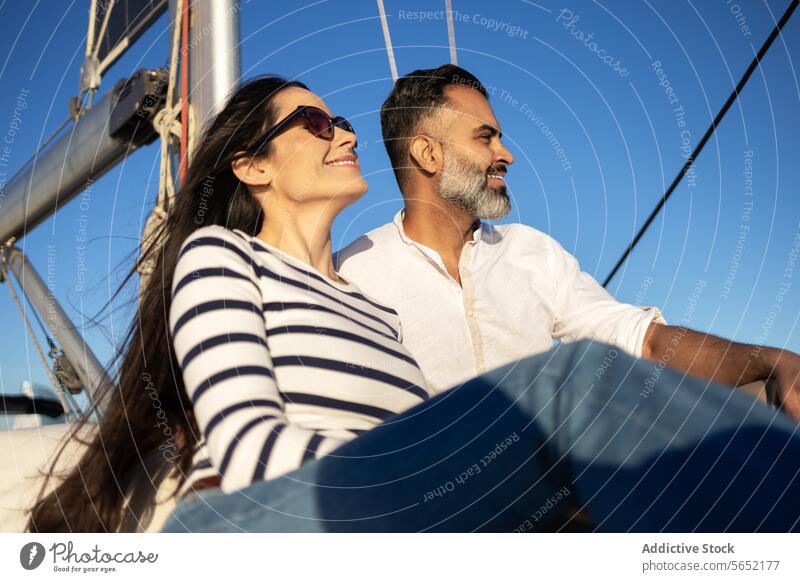 Smiling couple sitting on yacht smile pleasure enjoy relax sea happy trip romantic peaceful lifestyle casual adventure paradise embrace hug sailboat tourism