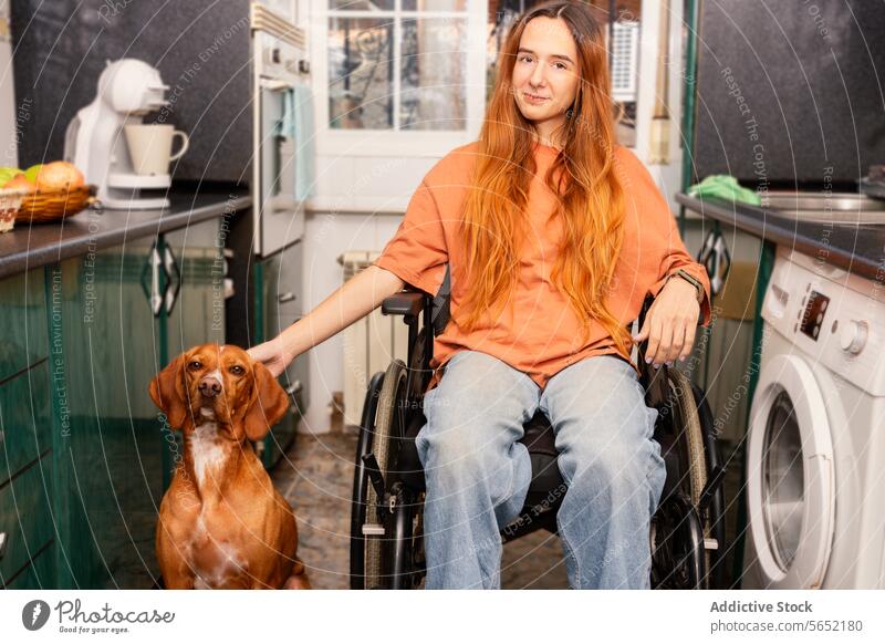 Young woman in wheelchair with loyal dog in kitchen pet home accessibility companionship indoor cozy disability appliance washing machine oven countertop