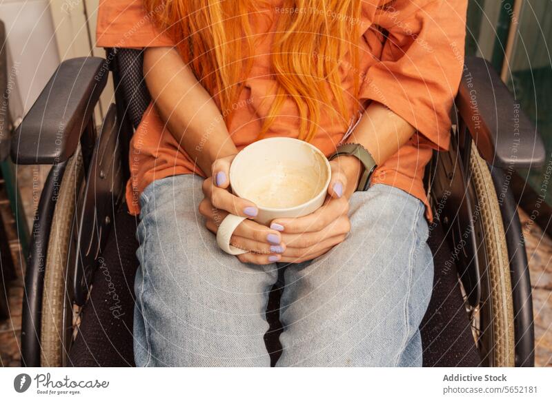 Person in a Wheelchair Holding a Coffee Cup wheelchair person coffee cup orange hair casual clothing seated disability relaxation beverage holding mug