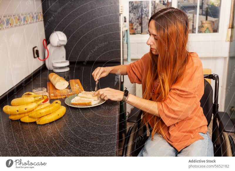 Woman in wheelchair preparing a meal in kitchen woman independence meal prep cutting bread sandwich home equipment cooking accessibility disability inclusion